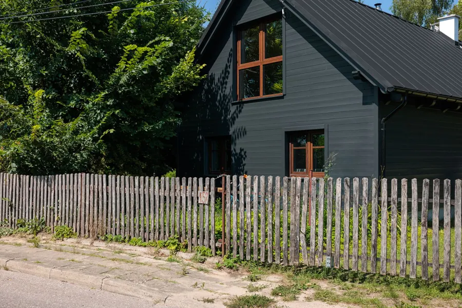 Grafitowy dom za drewnianym płotem