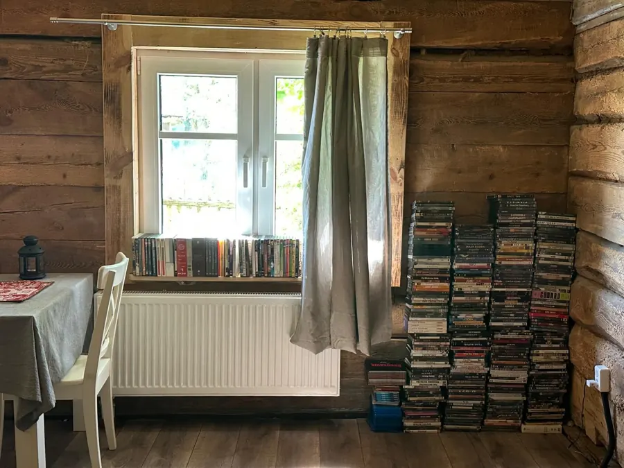 Stosy płyt DVD przy oknie w pokoju z bali